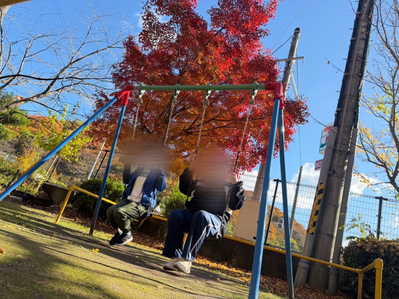 秋の紅葉を背景に、ブランコに座って楽しむ利用者の様子