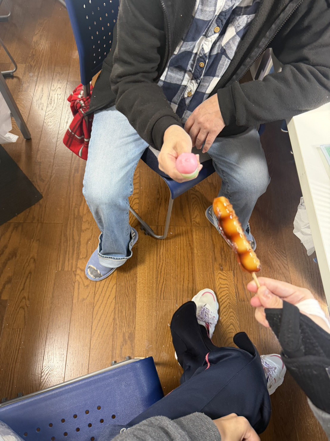 屋内で団子を手に持ち、利用者同士で団子をシェアしながら楽しむ様子